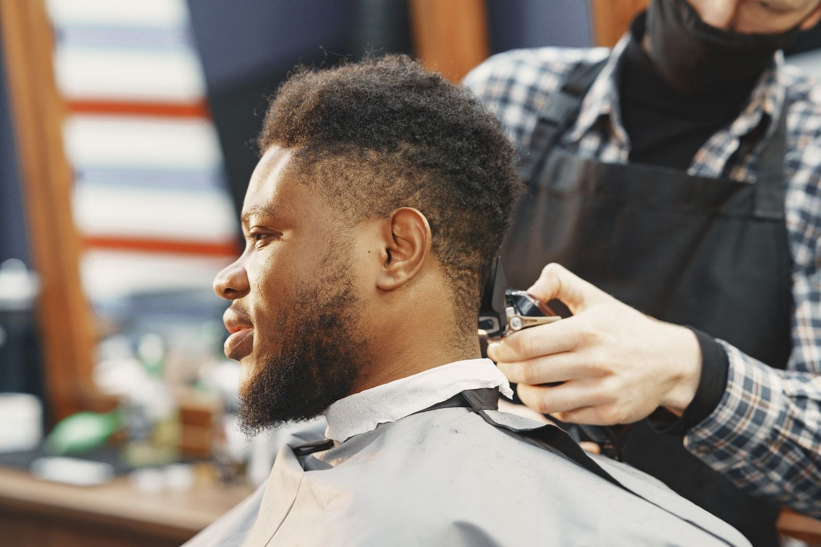 A barber trimming a customer's hair in a barbershop.