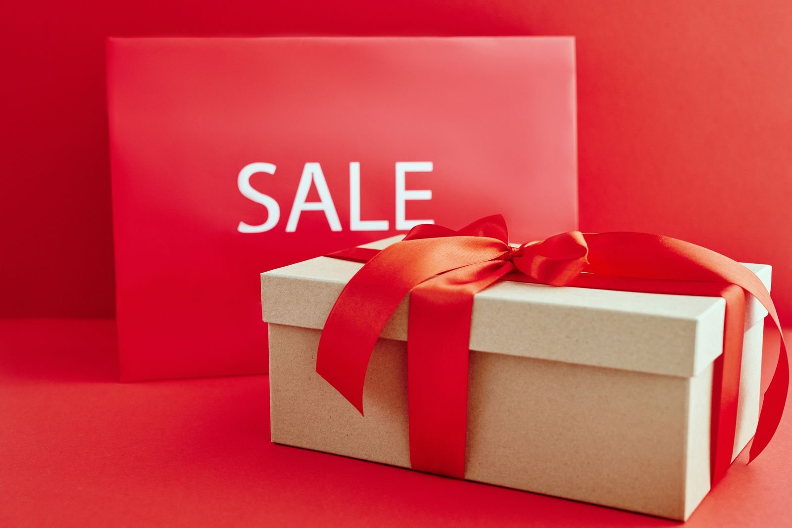 A sale sign beside a ribbon wrapped box illustrates an immediate discount offer.