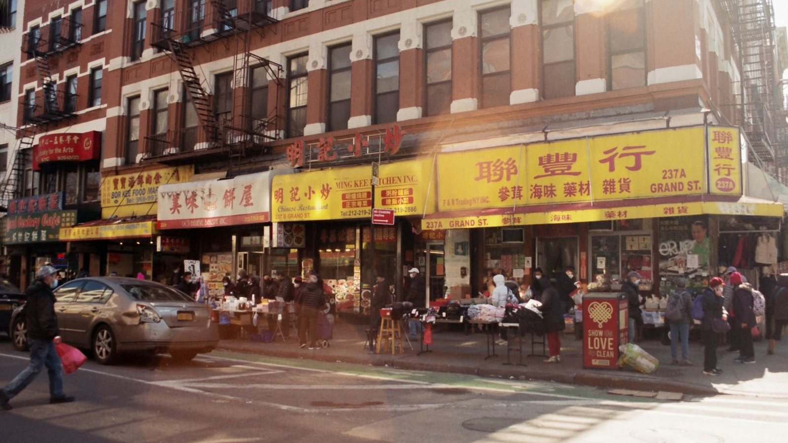 Shoppers and storefronts on a busy Chinatown street in New York City, United States.