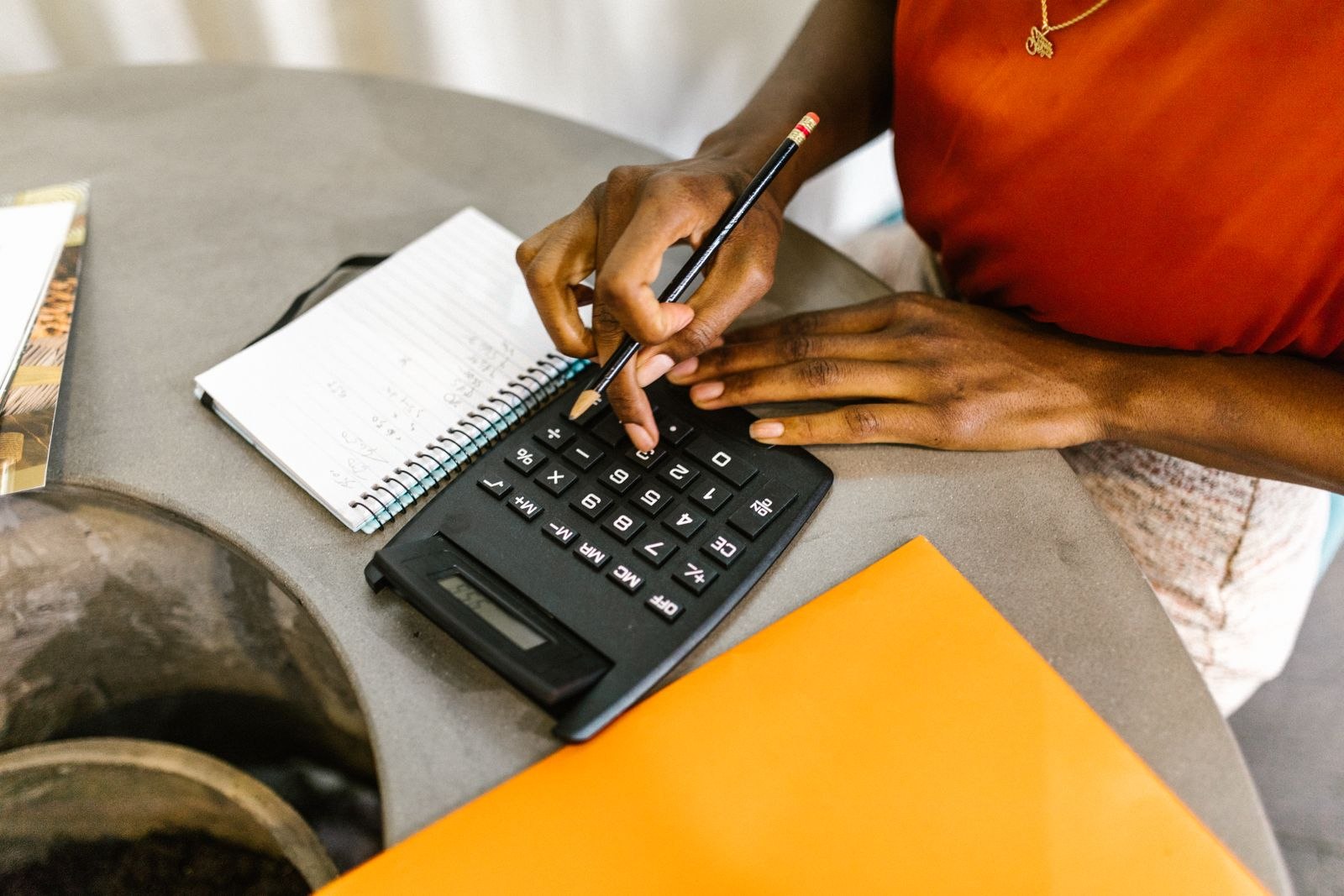 A woman using a calculator and notepad to review costs.