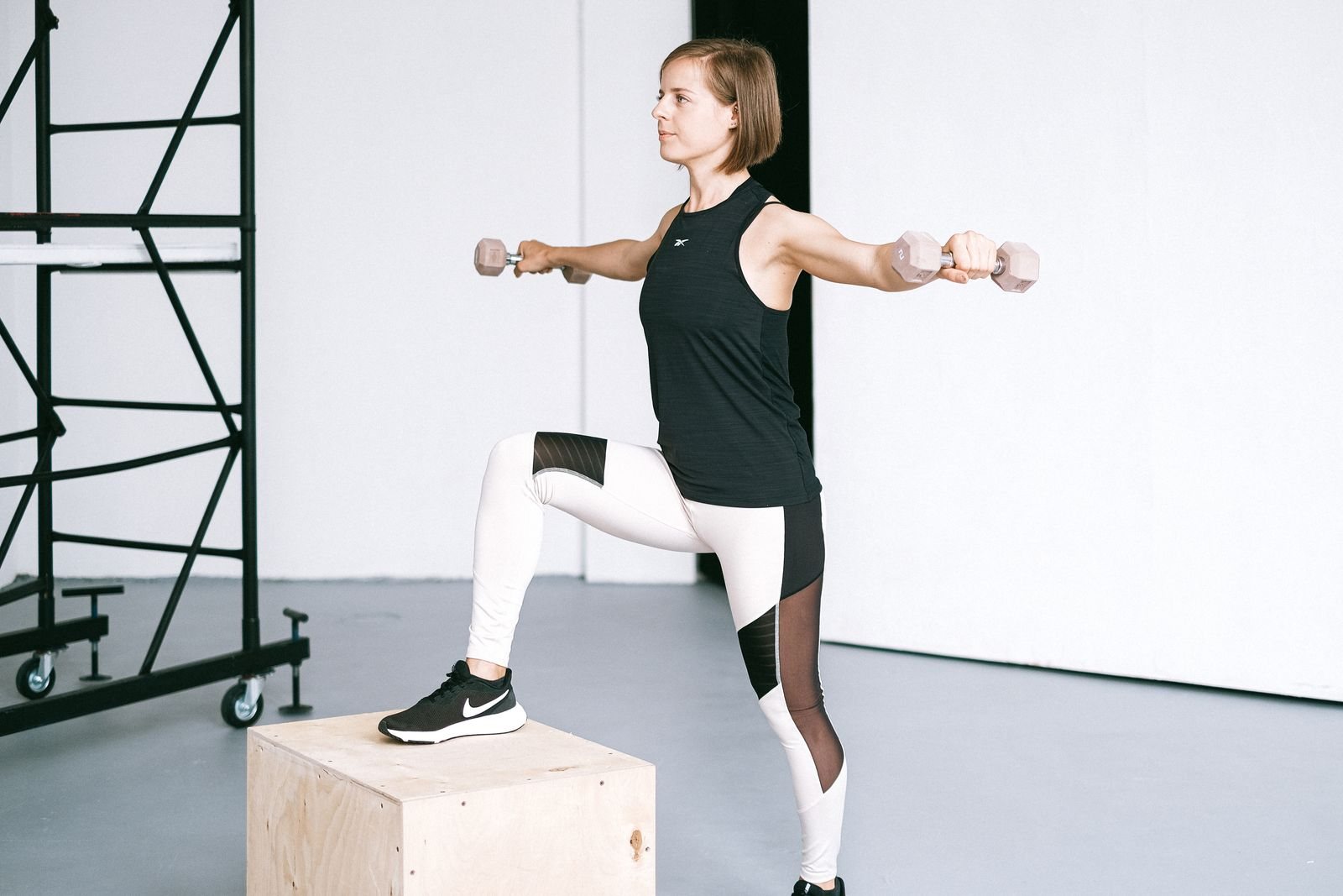 A woman exercising with dumbbells in a bright fitness studio.