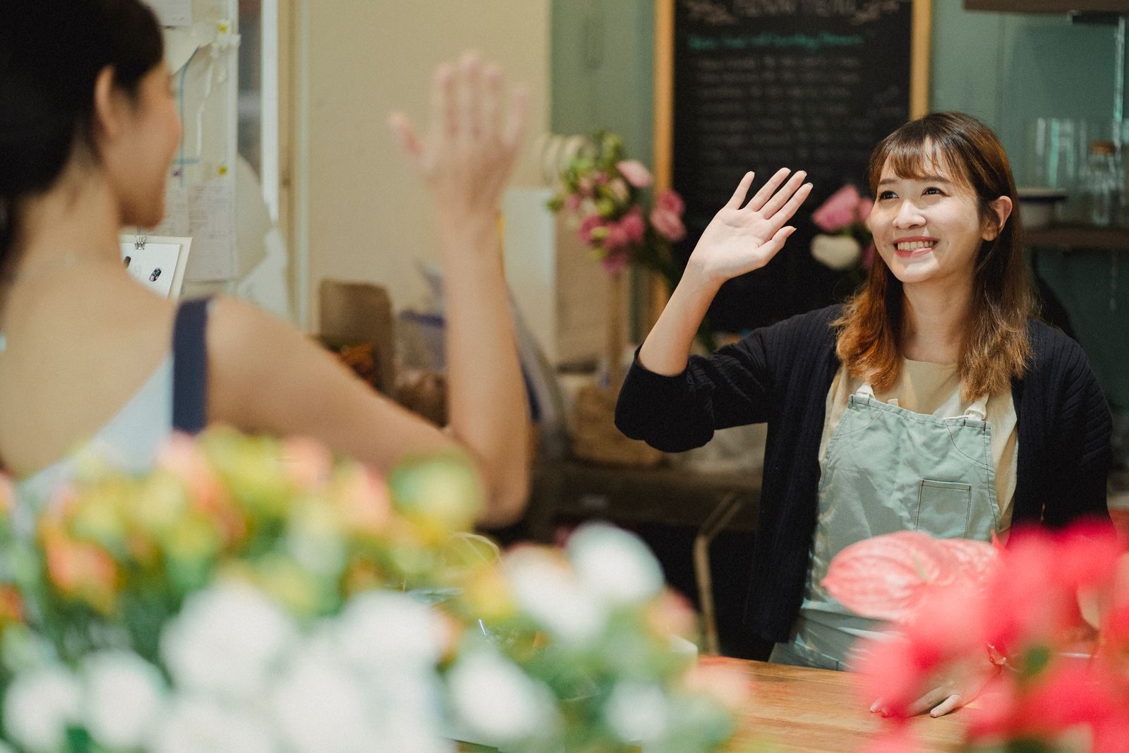 A florist greeting a customer inside a flower shop.